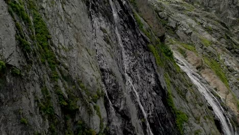 Tracking-and-top-shot-Air-shot-from-a-stream-of-water-splashing-waterfall-on-a-rock-wall-in-the-Caucasus-Mountains.-Around-the-jet-of-the-waterfall