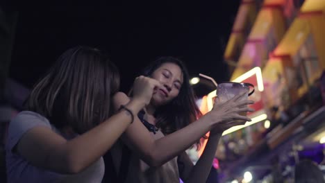 Slow-Motion---Reisende-Backpacker-asiatische-Frauen-Lesben-LGBT-Paare-tanzen-zusammen.-Weibliche-Alkohol-oder-Bier-mit-Freunden-trinken-und-feiern-auf-der-Khao-San-Road-in-Bangkok,-Thailand.