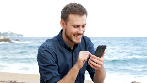 Hombre-viendo-el-contenido-del-teléfono-en-la-playa