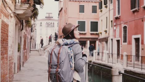 Glücklich-schönen-touristischen-Mädchen-fotografieren-Smartphone-zu-Fuß-in-der-erstaunlichen-Wasserkanal-Straße-in-Venedig-Italien-Slow-Motion.