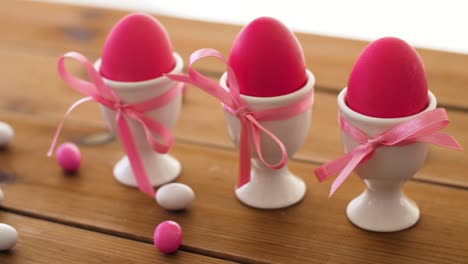 pink-easter-eggs-in-holders-and-candies-on-table