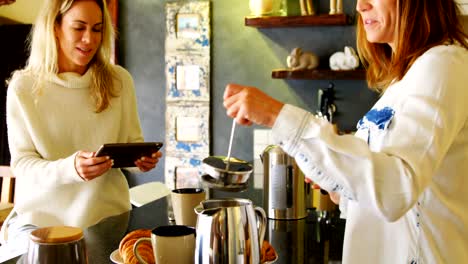 Pareja-de-lesbianas-preparando-café-y-uso-de-tableta-digital-en-cocina-4k