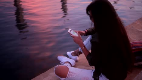 Young-Asian-skater-woman-texting-on-smartphone-by-the-sea