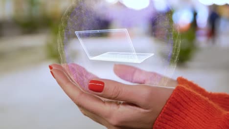 Female-hands-holding-a-conceptual-hologram-with-ultra-laptop