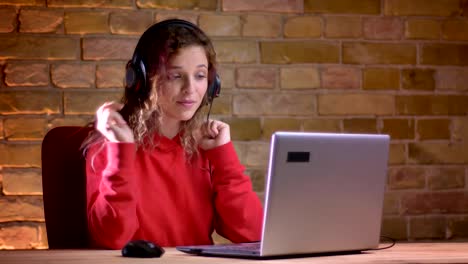 Retrato-de-la-joven-bloguera-femenina-en-rojo-con-capucha-grabación-de-vídeo-con-el-ordenador-portátil-en-el-fondo-de-la-pared-Bricken.