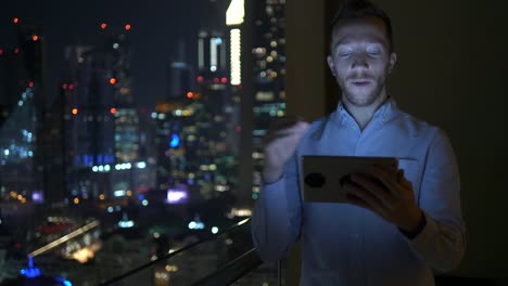 Young-man-using-tablet-to-speak-and-communicate-with-skyscraper-view-background