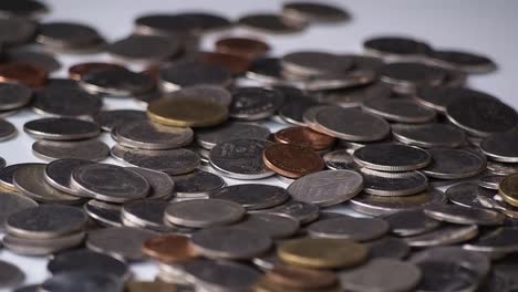 close-up-motion-footage-of-money-coins-falling-to-pile-of-coins-on-white-floor.-business,-financial-for-money-saving-or-investment-concept