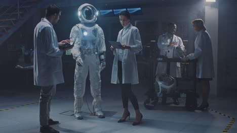 Team-of-Aerospace-Engineers-Design-New-Space-Suit-Adapted-for-Galaxy-Exploration-and-Travel.-Group-of-Scientists-Wearing-White-Coats-have-Discussion,-Use-Computers.-Constructing-Astronaut-Helmet