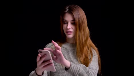 Closeup-portrait-of-young-pretty-caucasian-female-tapping-on-the-phone-in-front-of-the-camera