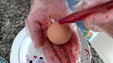 A-woman-in-gloves-paints-eggs