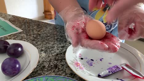 A-woman-in-gloves-paints-eggs