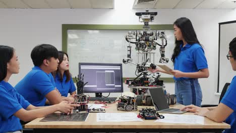 La-mujer-ingeniera-asiática-presenta-la-innovación-de-robots-con-el-equipo-de-diseño-de-arquitectos-en-laboratorio.-La-reunión-en-equipo-comparte-ideas-tecnológicas-y-un-robot-de-desarrollo-colaborador.-Concepto-de-tecnología-robótica-de-presentaci�