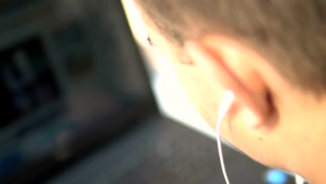 Handsome-male-teen-with-earphones-watching-movie-on-laptop-computer,-cinematic-selective-focus