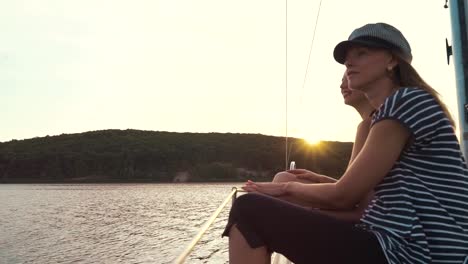 zwei-lesbische-Frauen-halten-Hände-auf-Segelboot-und-beobachten-Sonnenuntergang