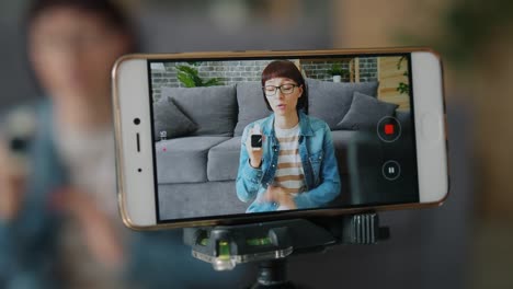 Blogger-aufnahme-Video-über-digitale-Uhr-mit-Smartphone-Kamera-zu-Hause