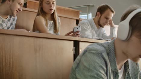 Hübsche-Mädchen-Studenten-sind-mit-DemSmartphone,-Beobachten-des-Bildschirms,-reden-und-lachen-sitzen-an-Den-Tischen-an-der-Universität.-Social-Media,-Internet,-Millennials-und-Bildungskonzept.