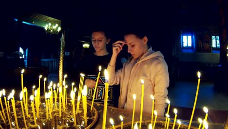 Two-girls-light-candles-and-praying-in-a-large-church