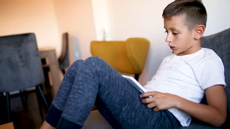 Young-boy-is-playing-games-on-his-tablet-at-home