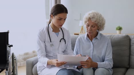 Médico-joven-consultar-abuela-vieja-discapacitada-mostrar-resultados-de-pruebas-médicas