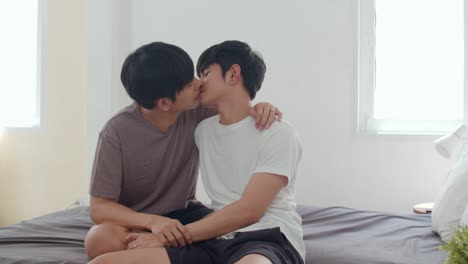 Asiatische-Homosexuell-Paar-küssen-auf-dem-Bett-zu-Hause.-Junge-asiatische-LGBTQ-Männer-glücklich-entspannen-sich-zusammen-verbringen-romantische-Zeit-nach-dem-Aufwachen-im-Schlafzimmer-zu-Hause-im-Morgen-Konzept.-Zeitlupe-Schuss.