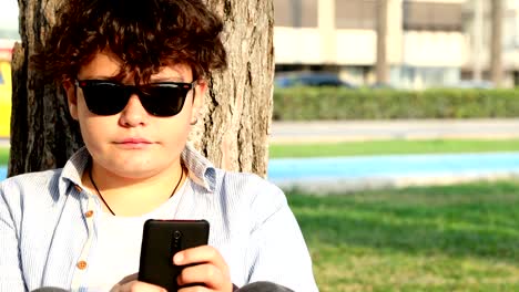 Teenage-boy-sitting-at-the-outdoor-with-smartphone