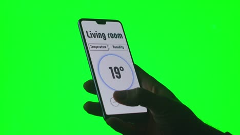 Die-Hand-steuert-die-Systeme-eines-modernen-technologischen-Zuhauses-mit-Handy-Apps-auf-einem-grünen-Hintergrund-Chromakey-für-Keying