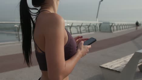 Sportlerin-mit-Smartphone-auf-Brücke.