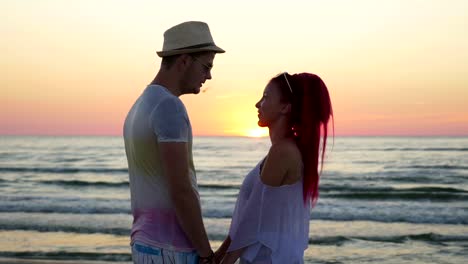 Romantisches-Paar-Hand-in-Hand-und-Blick-auf-den-Horizont-am-Strand-bei-Sonnenuntergang