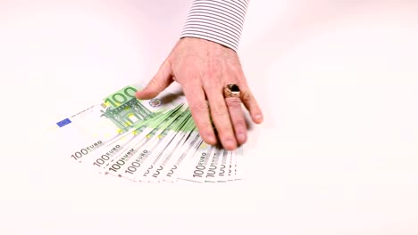 Man's-hand-spread-the-100-Euro-banknotes-on-the-table