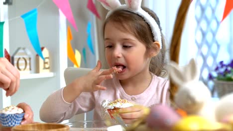 Joven-madre-y-su-hija-con-orejas-de-conejo-cocinar-cupcakes-de-Pascua