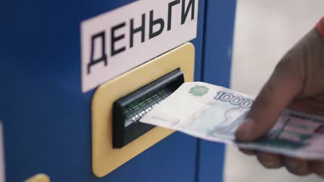 Person's-hand-sticks-a-paper-money-bill-into-the-banknote-bill-acceptor.-Clip.-Bill-acceptor