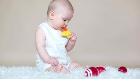 Cute-little-toddler-baby-boy,-playing-with-colorful-easter-eggs-and-little-decorative-ducks,-isolated-shot,-beige-background