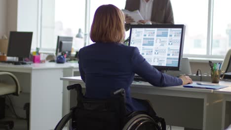 Mujer-en-silla-de-ruedas-con-colega-de-trabajo-en-oficina