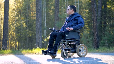 Un-hombre-en-silla-de-ruedas-mira-a-su-alrededor-en-un-bosque.