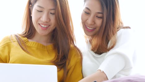 Pareja-de-lesbianas-asiática-jóvenes-utilizando-la-computadora-portátil-en-la-habitación-en-la-casa.