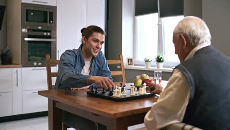 Cheerful-Young-Man-Playing-Chess-with-Grandfather