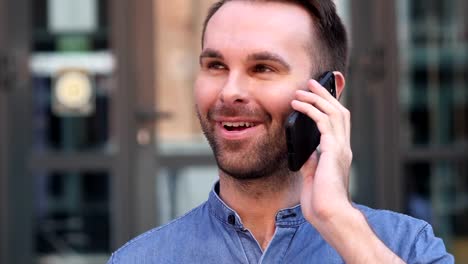 Young-Man-Talking-on-Phone,-Negotiating-in-Good-Mood