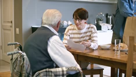 Cheerful-Social-Worker-Helping-Elderly-Man-with-Bills