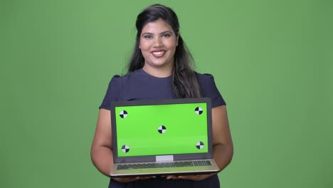 Young-overweight-beautiful-Indian-businesswoman-against-green-background