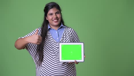 Young-overweight-beautiful-Indian-businesswoman-against-green-background