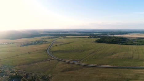 Flight-above-countryside-green-fields,-forest,-and-village-early-spring,-aerial-panoramic-view.