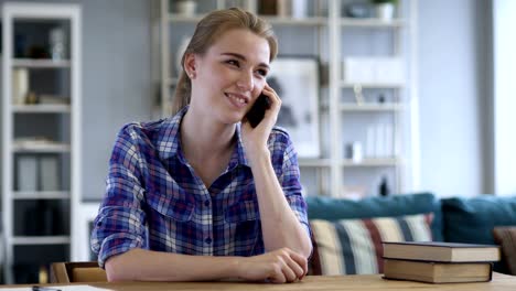 Joven-mujer-hablando-por-teléfono-mientras-relajante-en-silla