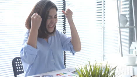 Beautiful-young-smiling-asian-woman-working-on-laptop-while-sitting-in-a-living-room-at-home.-Asian-business-woman-working-in-her-home-office.-Enjoying-time-at-home.