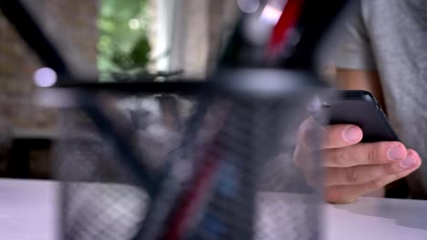 Moving-shot-of-man's-hand-typing-on-phone-in-office