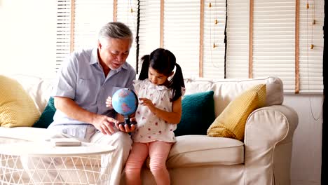 Senior-man-and-little-girl-reading-book-together-at-home.-people-with-family,-lifestyle,-education-concept.-4k-resolution.