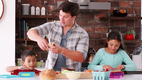 Padre-de-ayudar-a-los-niños-para-hacer-sándwiches-para-el-almuerzo-en-cocina