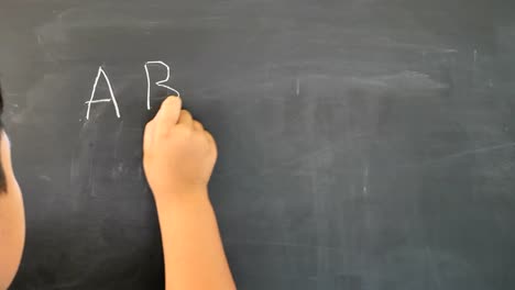 Hand-von-jungen-asiatischen-Kindern-die-Tafel-zu-schreiben.-Bildungskonzept.