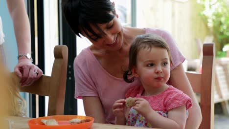 Niña-sentada-en-su-regazo-de-las-madres-tratando-de-nuevos-alimentos