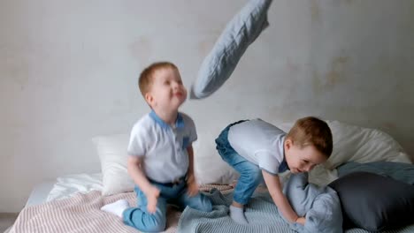 Niños-pequeños-los-muchachos-de-Twin-están-acostado-en-la-cama,-tirar-almohadas,-saltando-y-riendo.