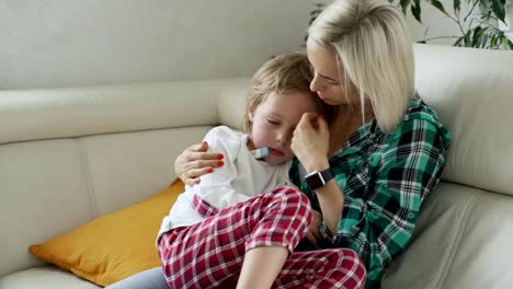 Medir-la-temperatura-de-su-hijo-enfermo-en-el-fondo-la-madre.-Niño-enfermo-con-alta-fiebre-en-el-sofá-en-casa